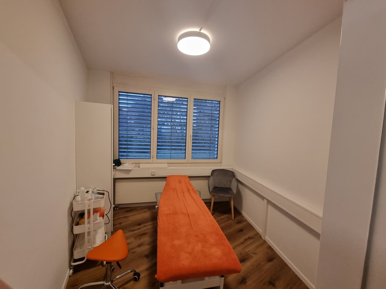Behandlungsraum mit orangefarbener Therapieliege in Geroldswil