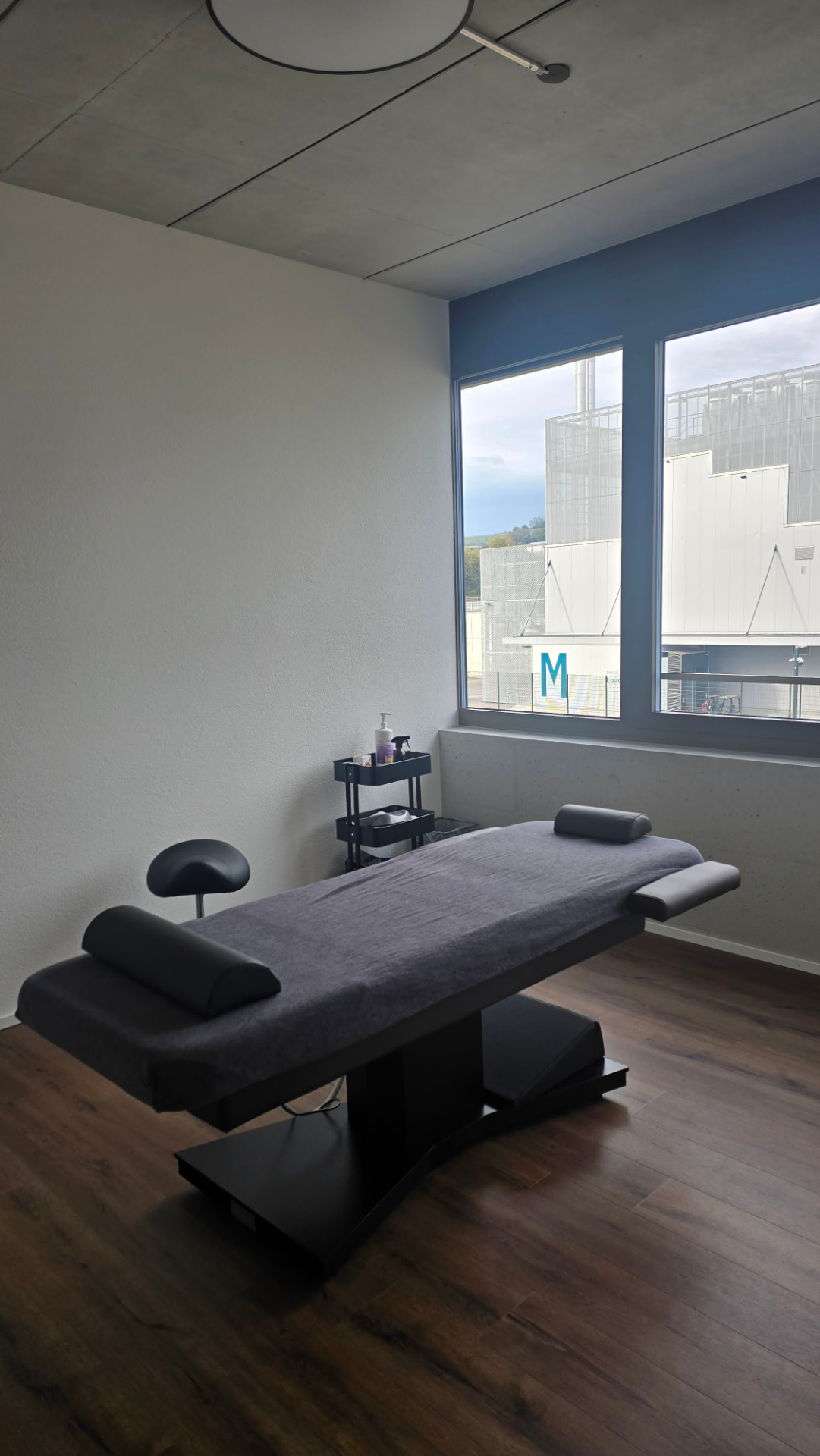 Helles Behandlungszimmer mit Therapieliege am Fenster